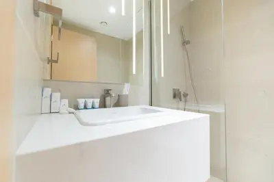 a white bathroom with a sink and a shower at Modern Aura Living Chic 1BR Hideaway in JVC in Dubai
