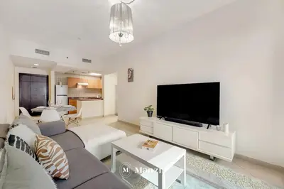 a living room with a couch and a flat screen tv at Cozy 1BR Apartment in Dubai Marina with City Views in Dubai