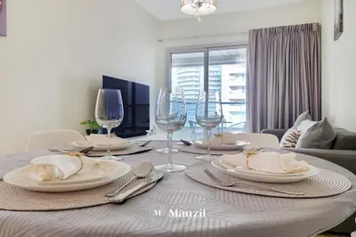 a dining room table with plates and wine glasses at Cozy 1BR Apartment in Dubai Marina with City Views in Dubai