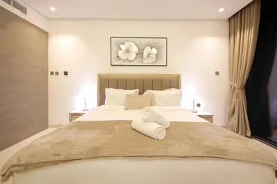 a bedroom with a large white bed with towels on it at Luxury 1BR at Sterling East , Burj Khalifa Views in Dubai