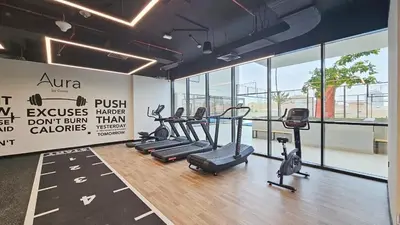 a gym with treadmills and ellipticals in a room with windows at New Studio Aura JVC Pool Gym Sauna Padel court in Dubai
