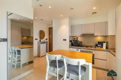 a kitchen with a wooden table and white chairs at Cozy 1BR for 3 with Community View by BMS in Dubai