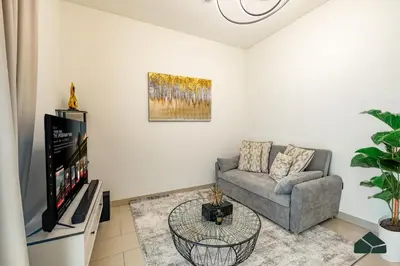 a living room with a couch and a tv at Cozy 1BR for 3 with Community View by BMS in Dubai