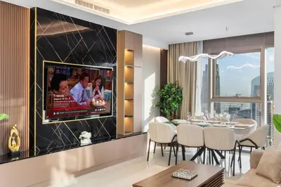 a living room with a television on a wall at Luxe High-Rise with Burj Khalifa and Sunset view in Dubai