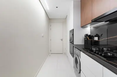 a white kitchen with a stove and a sink at Luxe High-Rise with Burj Khalifa and Sunset view in Dubai