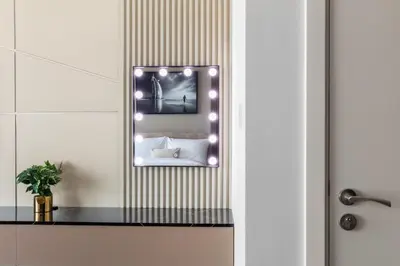 a mirror with lights on a wall in a bathroom at Luxe High-Rise with Burj Khalifa and Sunset view in Dubai