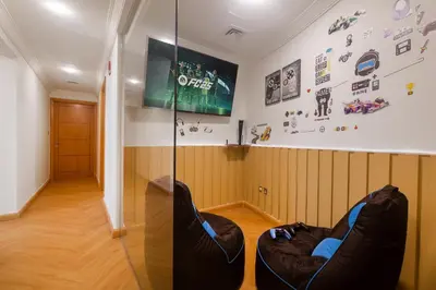 a room with two chairs and a tv on the wall at SkyHigh 4BR Penthouse Marina Views & Game Lounge Pool Table PS5 in Dubai