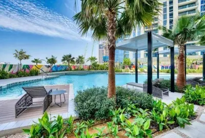 a swimming pool with a table and palm trees at Charming Studio with Cozy Vibes in Dubai