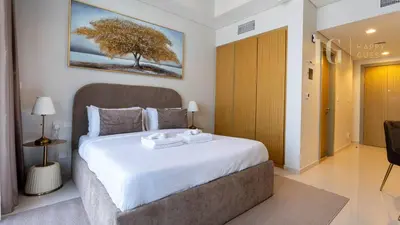 a bedroom with a large bed with a tree on the wall at Charming Studio with Cozy Vibes in Dubai