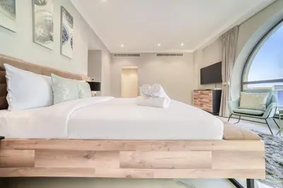 a bedroom with a large white bed and a chair at Hospitality Expert Rimal 5BR Marina Beach Pool in Dubai