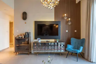a living room with a television and a blue chair at Designer 1 Bedroom Apartments in Dubai Hills Estate in Dubai
