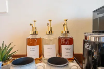 three bottles of syrup on a counter with a coffee maker at Designer 1 Bedroom Apartments in Dubai Hills Estate in Dubai