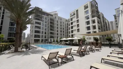 a patio with chairs and a pool and buildings at Rosewater at Creek Beach Building 2 Luxury Creekside Living with Beach & Pool Access in Dubai