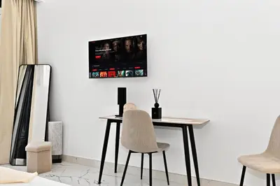 a table and chairs in a room with a tv on the wall at Azizi Riviera Gateway - Highest Floor Superior Apartment in Dubai