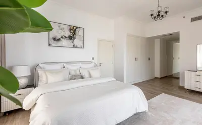a white bedroom with a large bed and a chandelier at Amazing, Spacious 2-bed with fantastic sea view! in Dubai