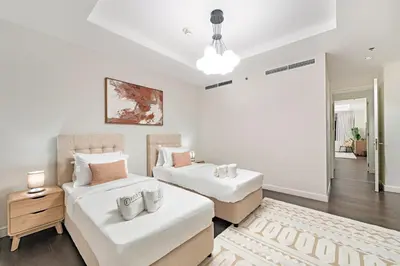a white room with two beds and a table at FIRST CLASS 2BR Spacious DIFC Living in Dubai