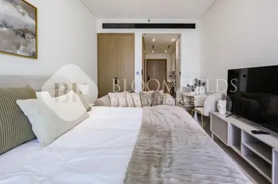 a bedroom with a large white bed and a flat screen tv at Bloomfields Fantastic Stu Binghatti Azure in Dubai