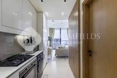 a kitchen with a stove top oven next to a living room at Bloomfields Fantastic Stu Binghatti Azure in Dubai