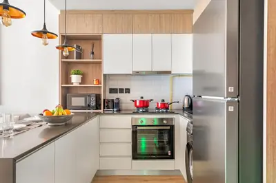 a kitchen with white cabinets and a stainless steel refrigerator at FIRST CLASS Studio Minimalist Chic Retreat in Dubai