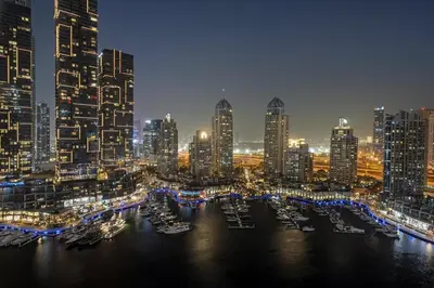 a city skyline at night with boats in the water at FIRST CLASS 1BR Majestic Marina Views in Dubai