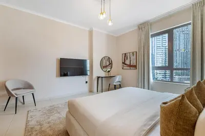 a bedroom with a large bed and a tv at Durrani Homes - Minimal Luxe 3BR with Burj Khalifa and fountain view - third room without partition in Dubai