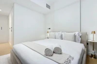 a white bedroom with a large white bed with two towels at FIRST CLASS 2BR Burj Views & Classy Comfort in Dubai