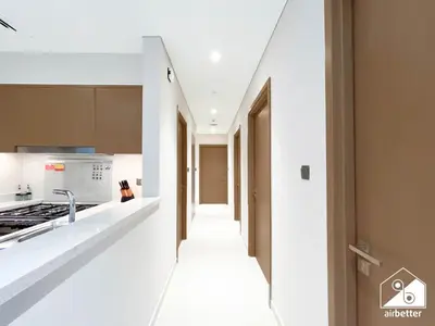 a kitchen with white countertops and a hallway at Skyline Elegance, Fountain View 3BR in Downtown in Dubai