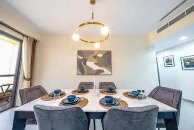 a dining room table with chairs and a chandelier at Luxury 2BR - Stunning Marina View and JBR Beach in Dubai