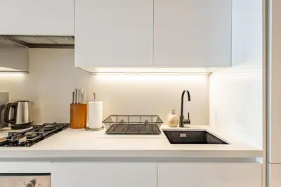a white kitchen with a sink and a stove at Deluxe Studio Business Bay - Balcony City Skyline Views in Dubai