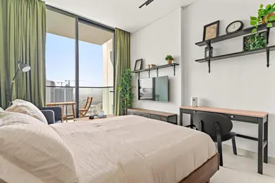 a bedroom with a bed and a desk and a desk at Modern Studio with Pool & Gym - Prime JVC Location in Dubai
