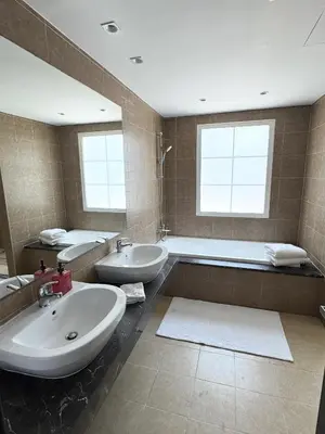 a bathroom with two sinks and a bath tub at Family Villa, Sleeps up to 9 in JVT and Large garden in Dubai