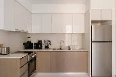 a kitchen with white cabinets and a stainless steel refrigerator at Burj Royale 1BR - Close to Burj Khalifa and Dubai Mall in Dubai