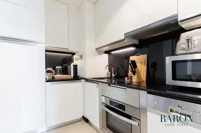 a kitchen with white cabinets and a microwave at The Majestic in Dubai