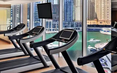 a gym with three treadmills in front of a window at The Glamorous in Dubai