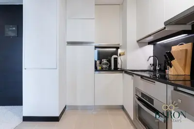 a kitchen with white cabinets and a refrigerator at The Glamorous in Dubai