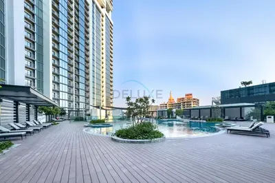 a view of a building with a pool and chairs at 1BR with Maid's Room, Few Minutes Drive to Downtown Dubai, Burj Khalifa, Dubai Mall, Close to Parks and Crystal Lagoons - The Crest Tower C, Sobha Hartland by Deluxe Holiday Homes in Dubai