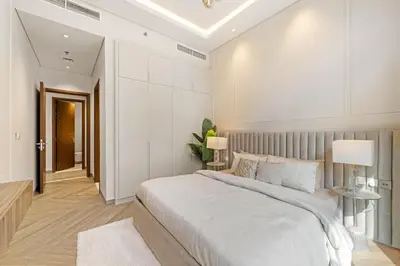 a white bedroom with a large bed and two lamps at Brand New Stylish Unit near Circle Mall in Dubai
