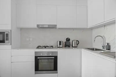 a white kitchen with a stove and a sink at Palace Residence Chic 2BR Creek Beach View in Dubai