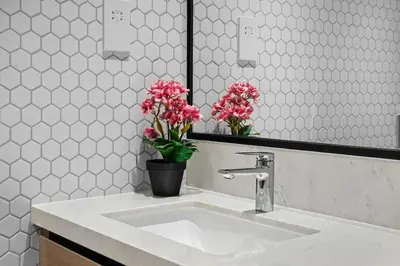 a bathroom with a sink and a mirror and pink flowers at Palace Residence Chic 2BR Creek Beach View in Dubai