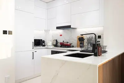 a white kitchen with white cabinets and a sink at Luxury Top Floor Apartment in JVC in Dubai