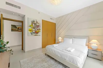 a white bedroom with a large white bed and two lamps at Lux Upscale Living Walk to Dubai Mall in Dubai