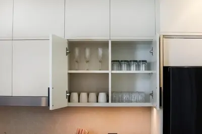 a kitchen with white cabinets with glasses and a refrigerator at Stylish 4BD Villa Opposite Pool & Park in Dubai