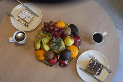 a plate of fruit on a table with a cup of coffee at Modern Studio, Burj Khalifa View, Upside Living in Dubai