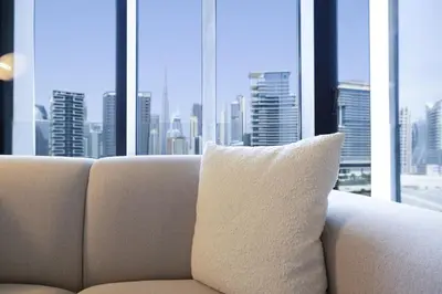 a white pillow sitting on a couch in front of a window at Modern Studio, Burj Khalifa View, Upside Living in Dubai
