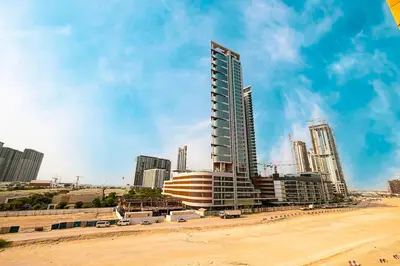 a tall building on a beach next to a city at Studio in Azizi Riviera in Dubai