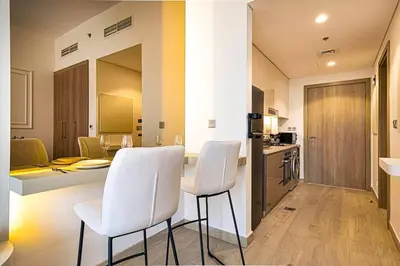 a kitchen and dining room with white chairs and a table at Studio in Azizi Riviera in Dubai
