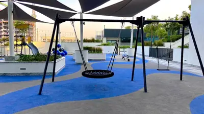 a swing set in a playground with blue carpet at Stylish 1BR Retreat in Sobha Crest with Balcony in Dubai