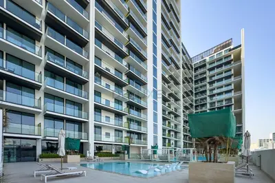 an apartment building with a swimming pool and a building at Near Gadaf Community Park, Few Minutes Walk to Circle Mall, Short Drive to Dubai Miracle Garden and Butterfly Garden - Binghatti Amber, JVC by Deluxe Holiday Homes in Dubai