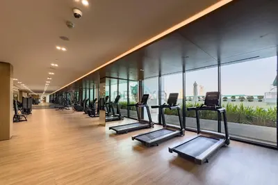 a row of treadmills in a gym with windows at Near Gadaf Community Park, Few Minutes Walk to Circle Mall, Short Drive to Dubai Miracle Garden and Butterfly Garden - Binghatti Amber, JVC by Deluxe Holiday Homes in Dubai