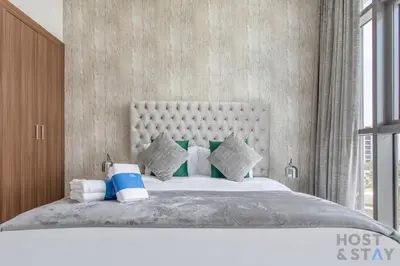 a bedroom with a large bed with a large window at Parkview 2BR in Orchid, Damac Hills in Dubai